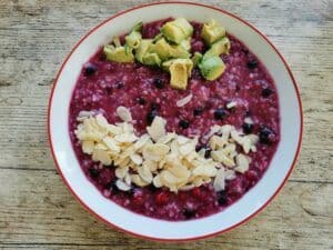 Frozen berries oatmeal with avocado as additional toppings.