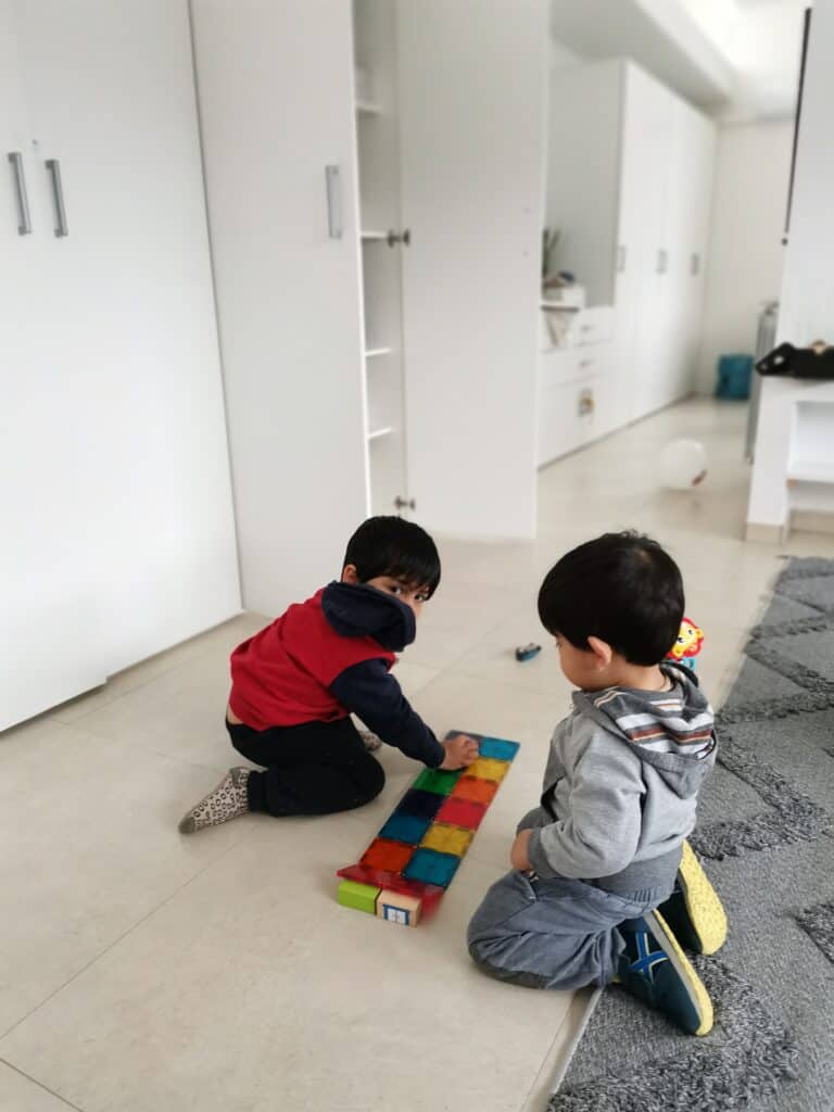 two toddler boys playing magic tiles at home.